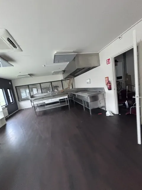 De oude keuken vóór de verbouwing, met roestvrijstalen werkbanken en een afzuigkap aan het plafond