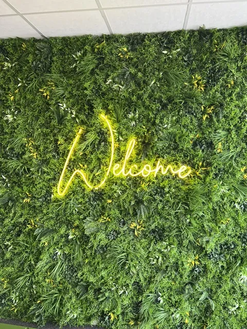 Het woord Welcome in geel neon op een groene moswand
