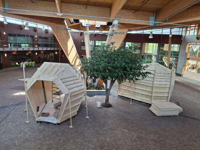 Twee houten hutten in aanbouw naast de kunstboom op het plein