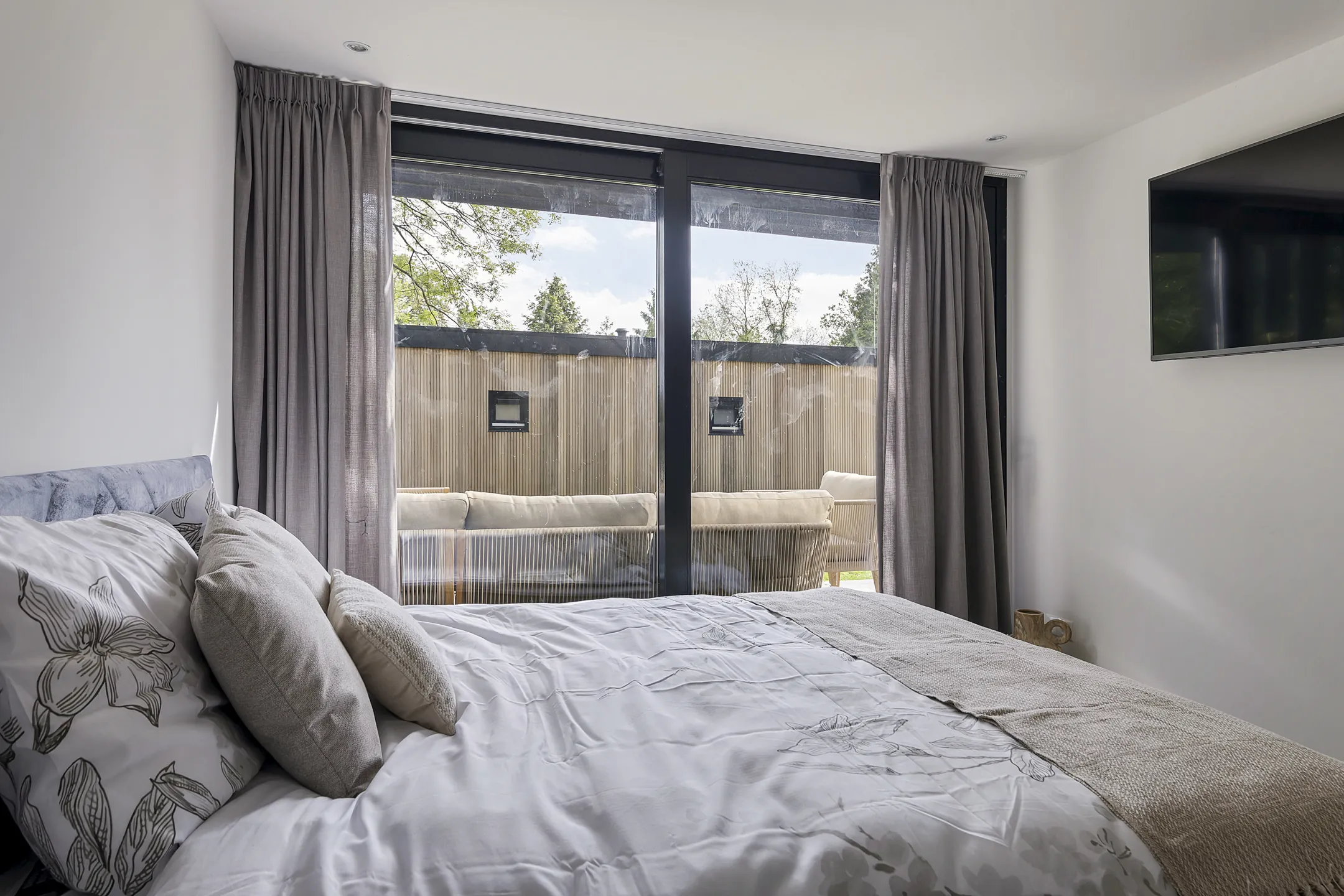 Een slaapkamer met een tweepersoonsbed en een schuifpui naar buiten