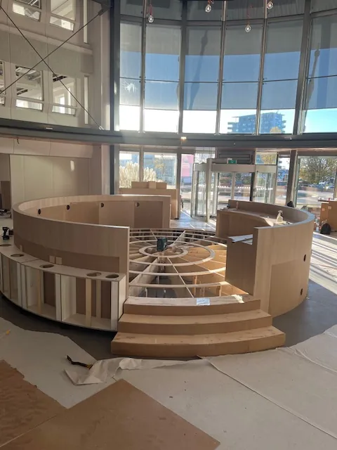 Het ronde houten podium in opbouw, met treden en de aanzet van de banken
