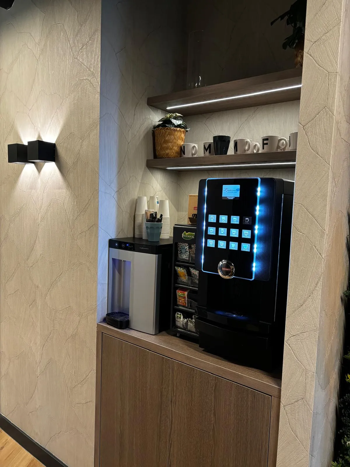 Koffienis met een eiken inbouwkast, zwevende planken met ledstrip en zwarte wandlampen op reliëfstuc