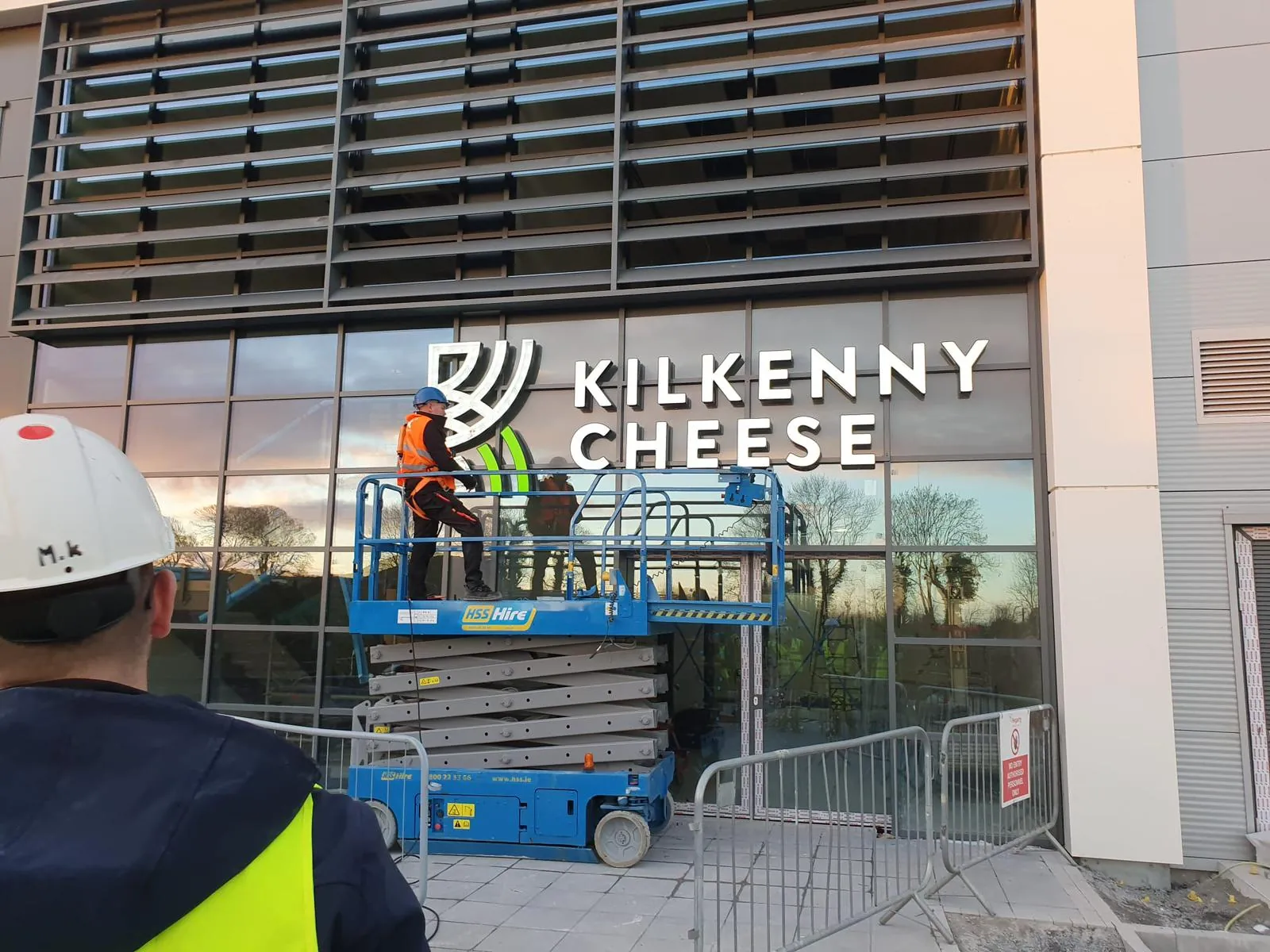 Een monteur op een hoogwerker plaatst de gevelletters van Kilkenny Cheese boven de glazen entree