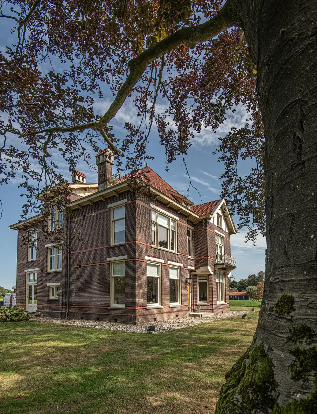 Het karakteristieke pand van Multiselect in Ruinerwold, gezien vanaf het gras onder een oude boom