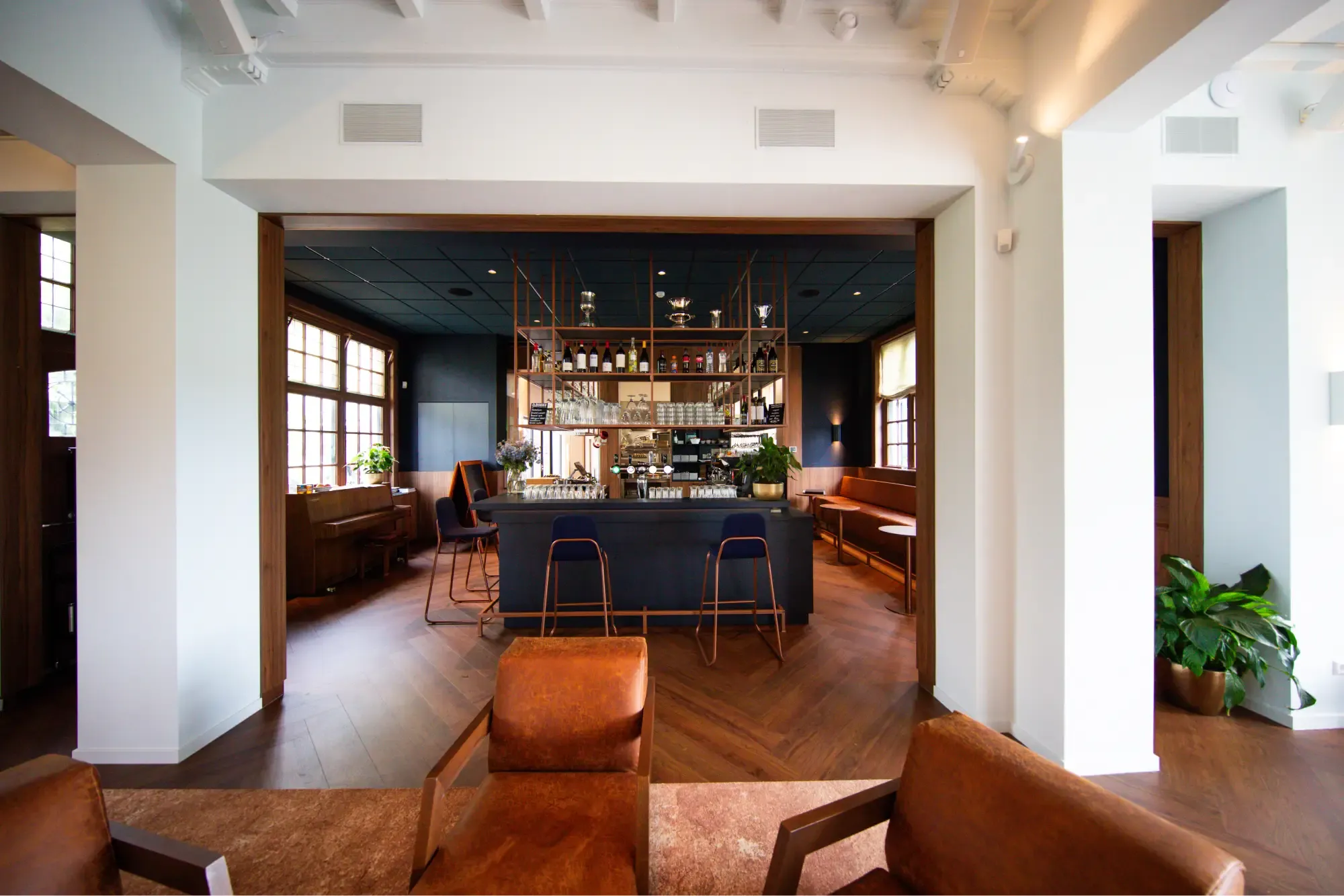De bar van het clubhuis met cognackleurige leren fauteuils en ronde tafels