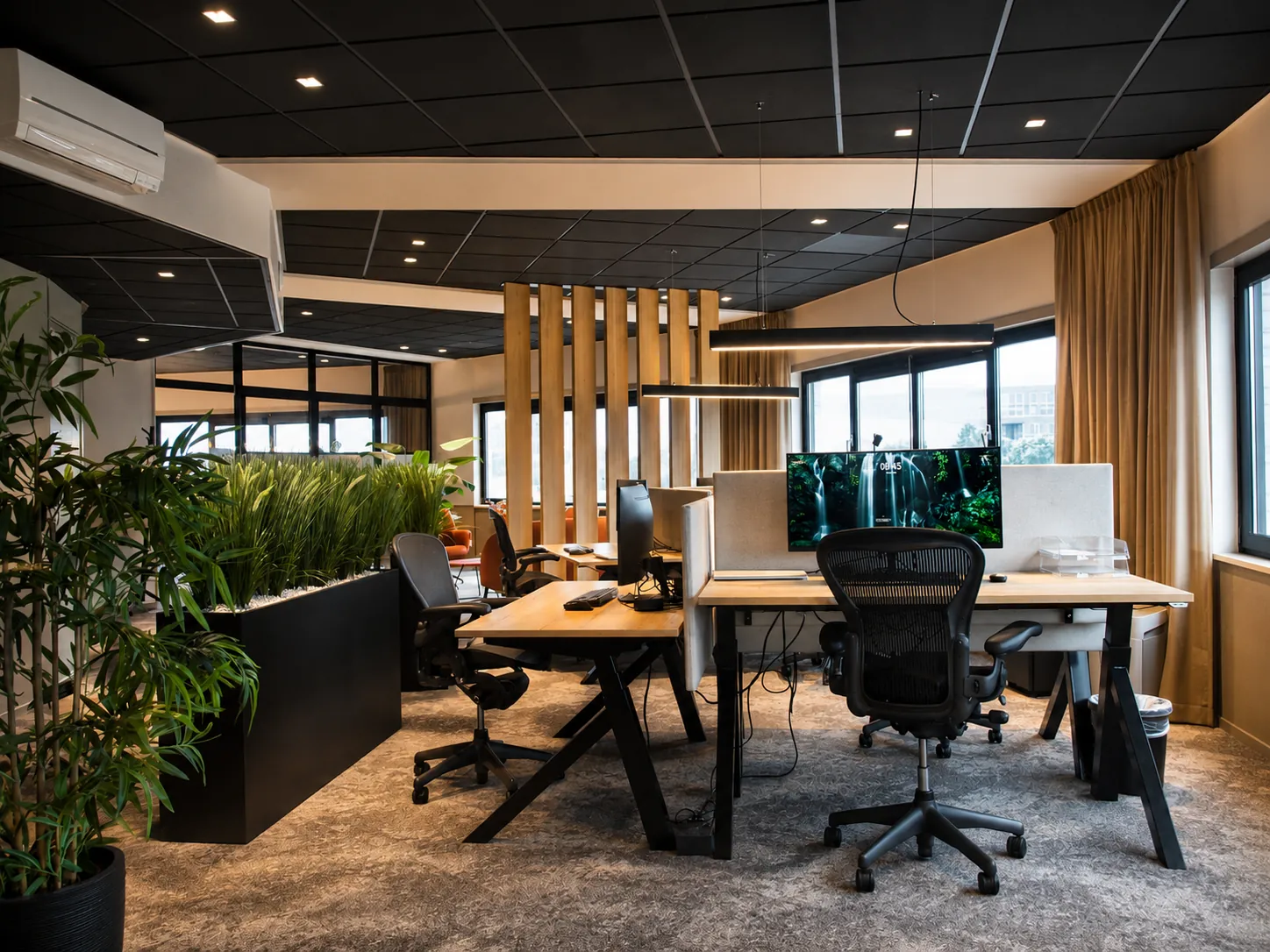 Kantoortuin met houten bureaus, zwarte plantenbakken met siergras en een scheidingswand van verticale eiken lamellen