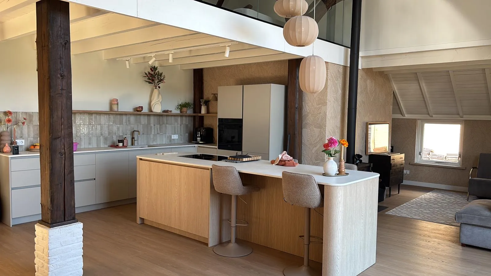 Het keukeneiland met houten front en barkrukken, met een oude houten stijl ervoor