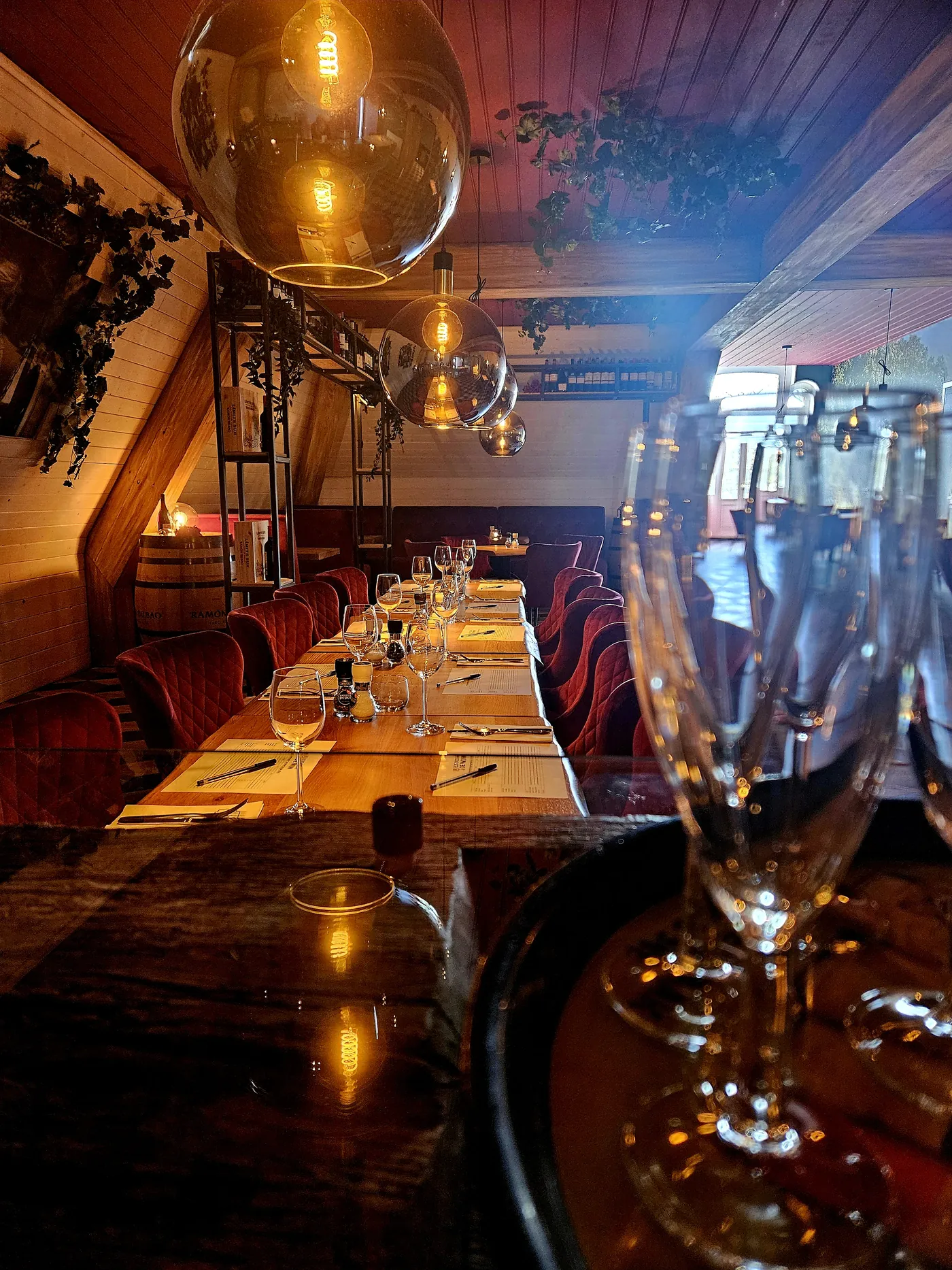 Een lange gedekte tafel met rode stoelen en wijnglazen in het licht