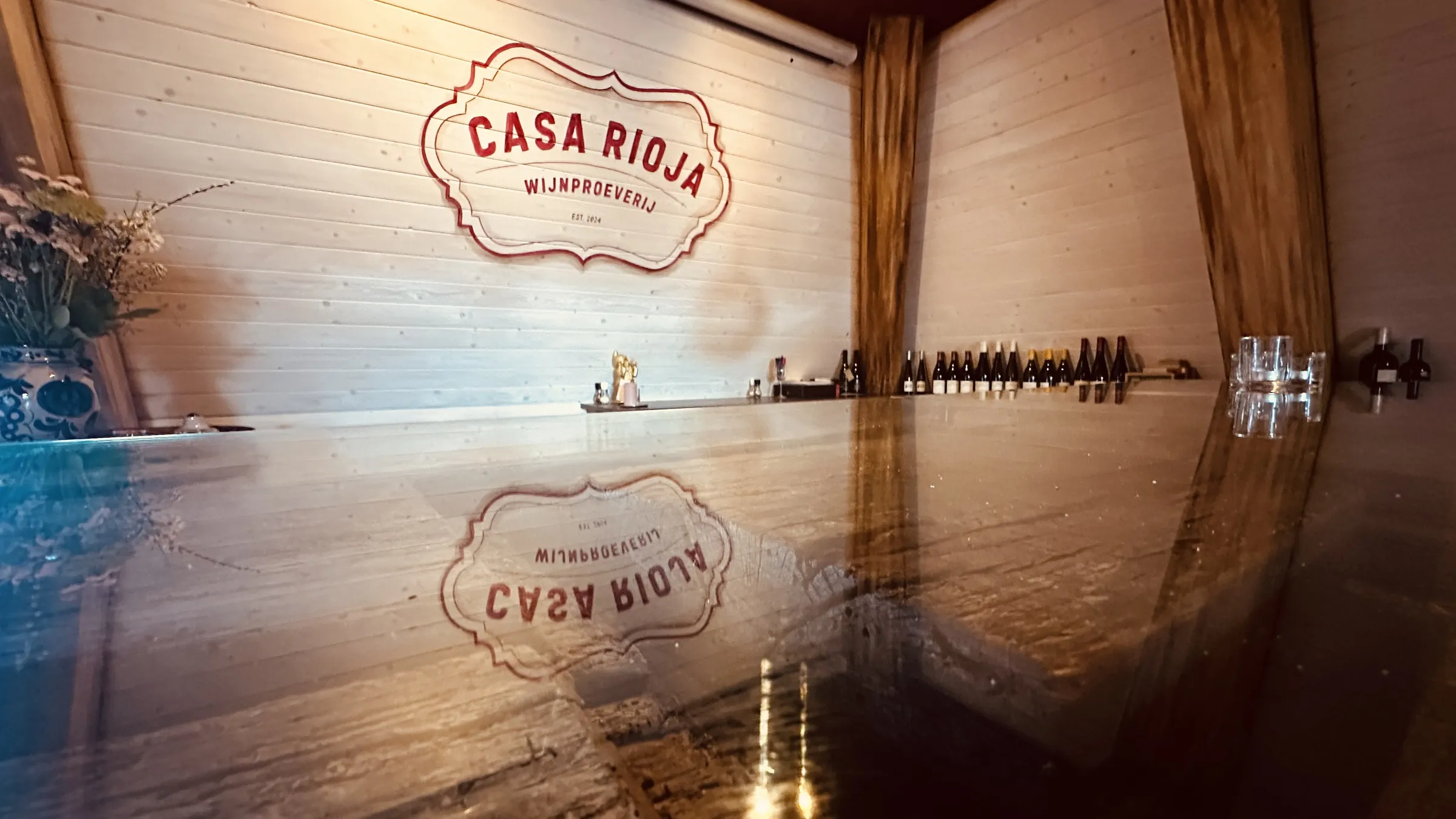 Het logo van Casa Rioja op de wand, weerspiegeld in een tafelblad