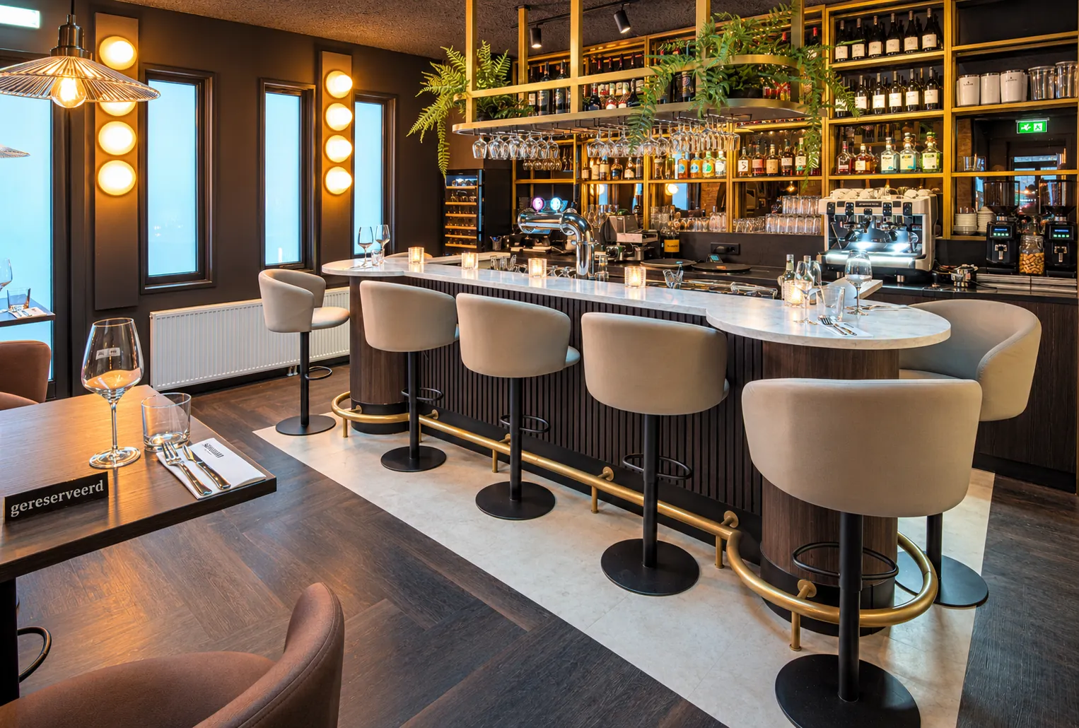 De ronde bar van Sondrio met marmeren blad, een rij beige krukken met gouden voetsteun en gouden rekken vol flessen