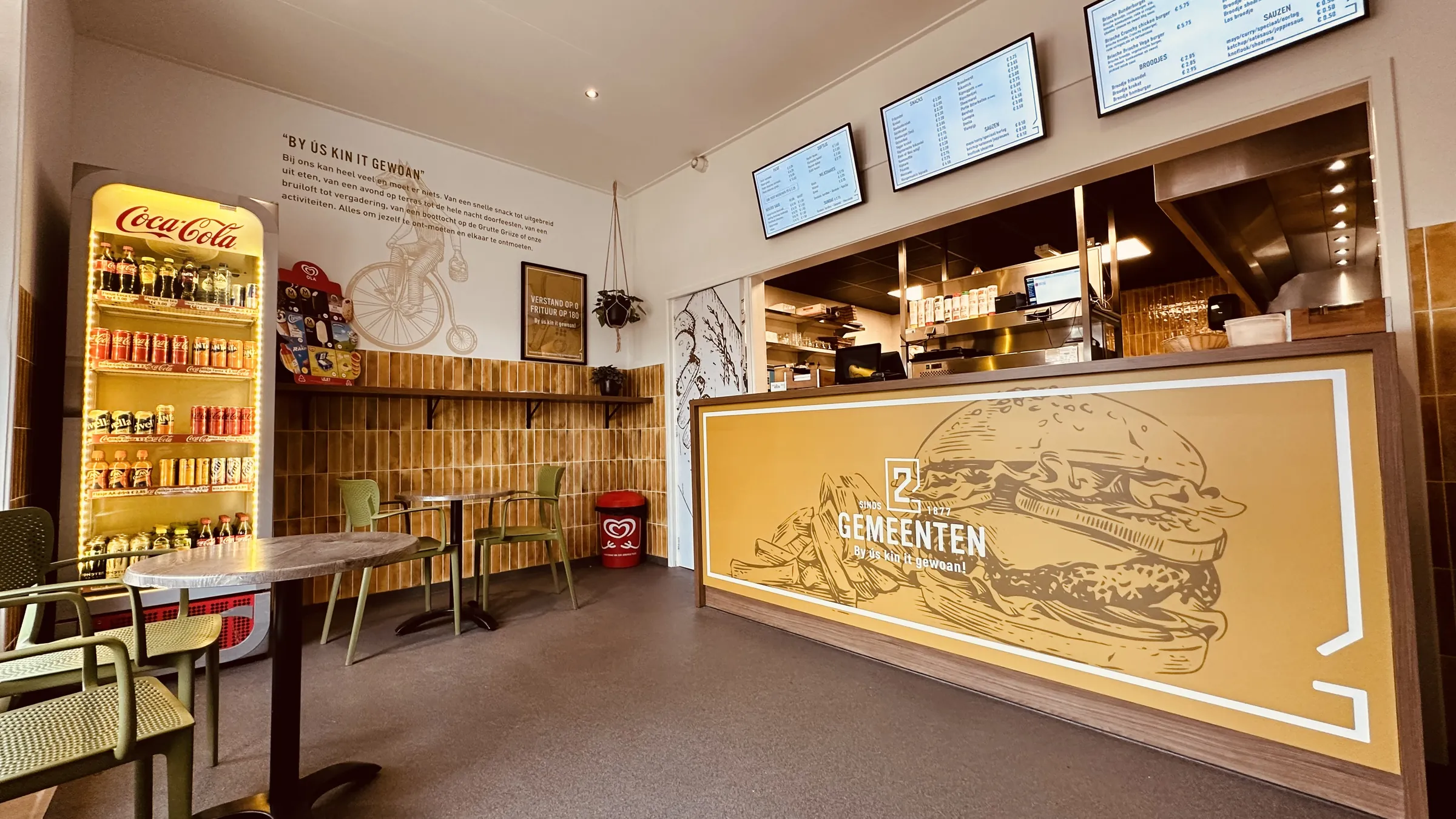 De opgeleverde snackbar met de gele balie, tegels en menuschermen