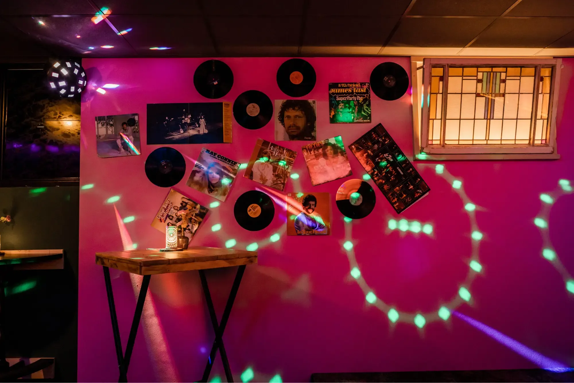 De karaokeruimte met roze muren, lp's aan de wand en discolicht