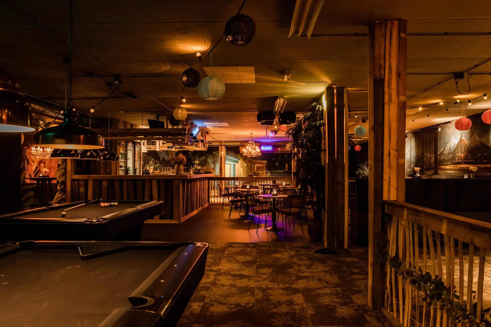 De speelhal van Pieter Poot met biljarttafels, een houten bar en lichtslingers