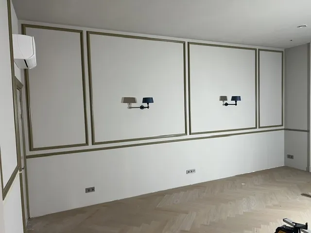 Nieuwe wandlijsten en wandlampen boven een net gelegde visgraatvloer