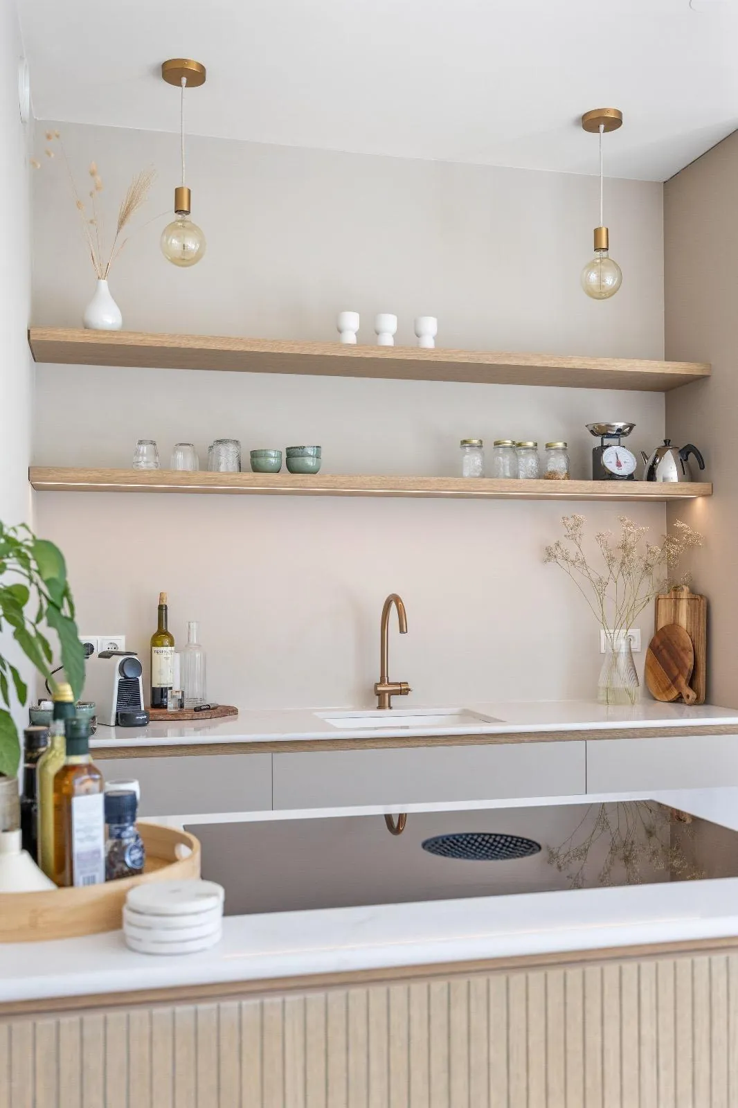 Zwevende houten planken met ledstrip, een koperkleurige kraan en een kookplaat in het houten schiereiland