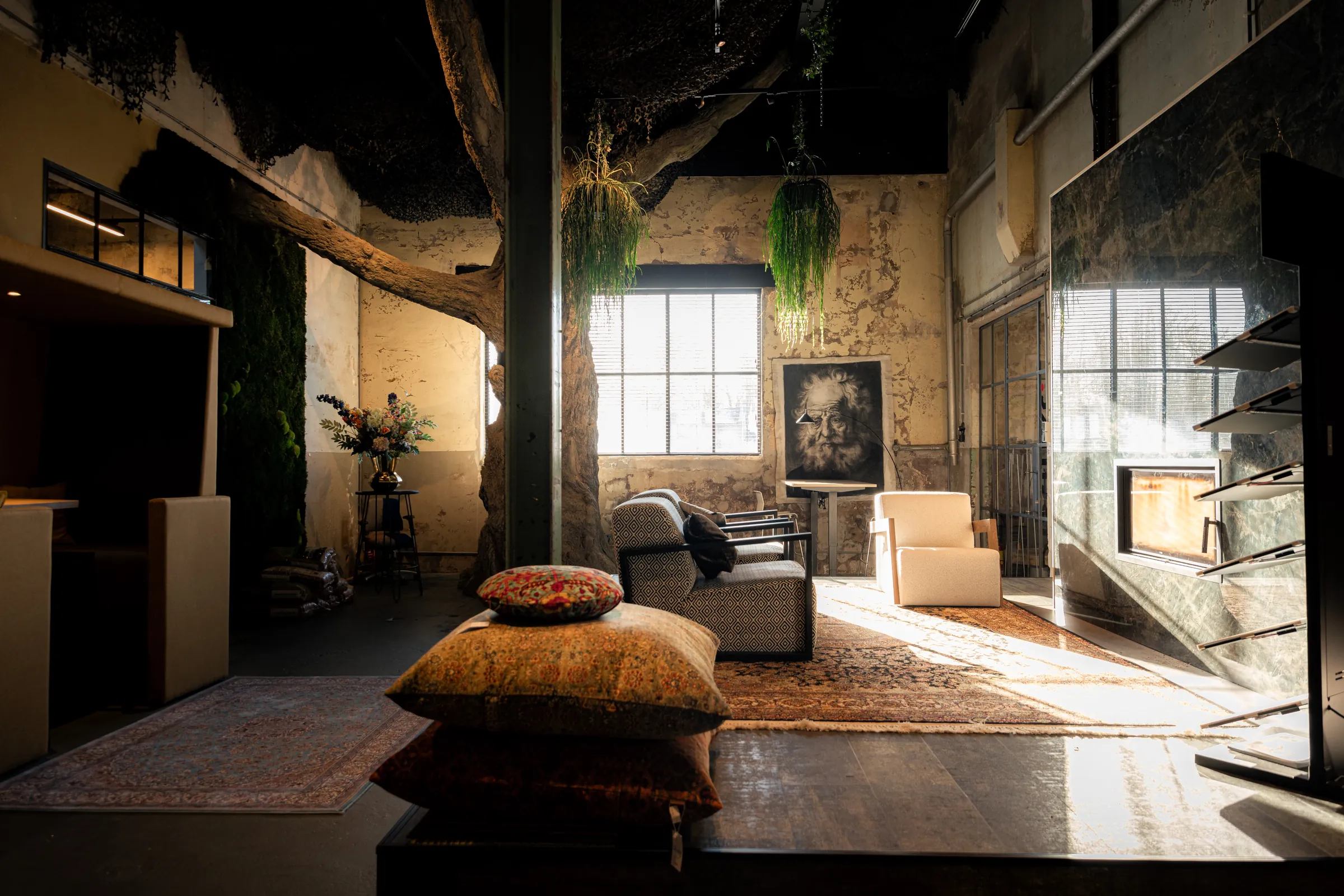 Een ruimte in het fabriekspand FJ08 in Joure met een grote kunstboom, fauteuils op Perzische tapijten en een groene marmeren haardwand in zonlicht